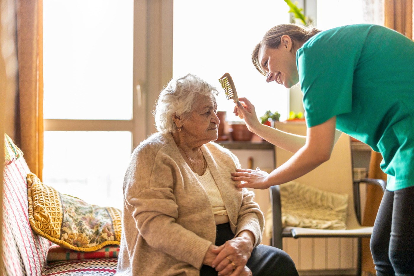 Carer combing elderly woman's hair 