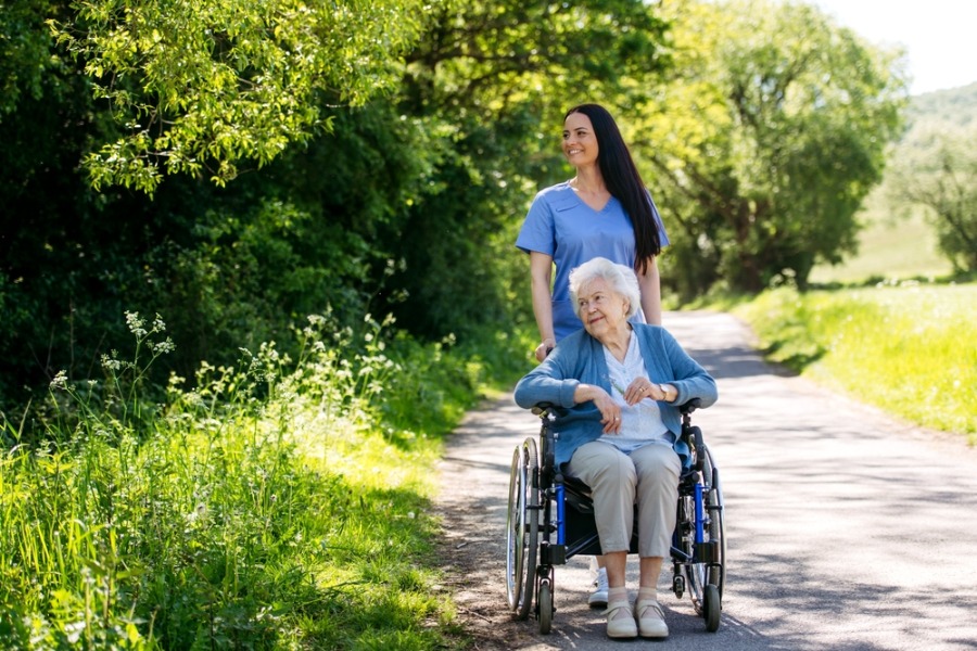 carer pushing elderly woman in chair