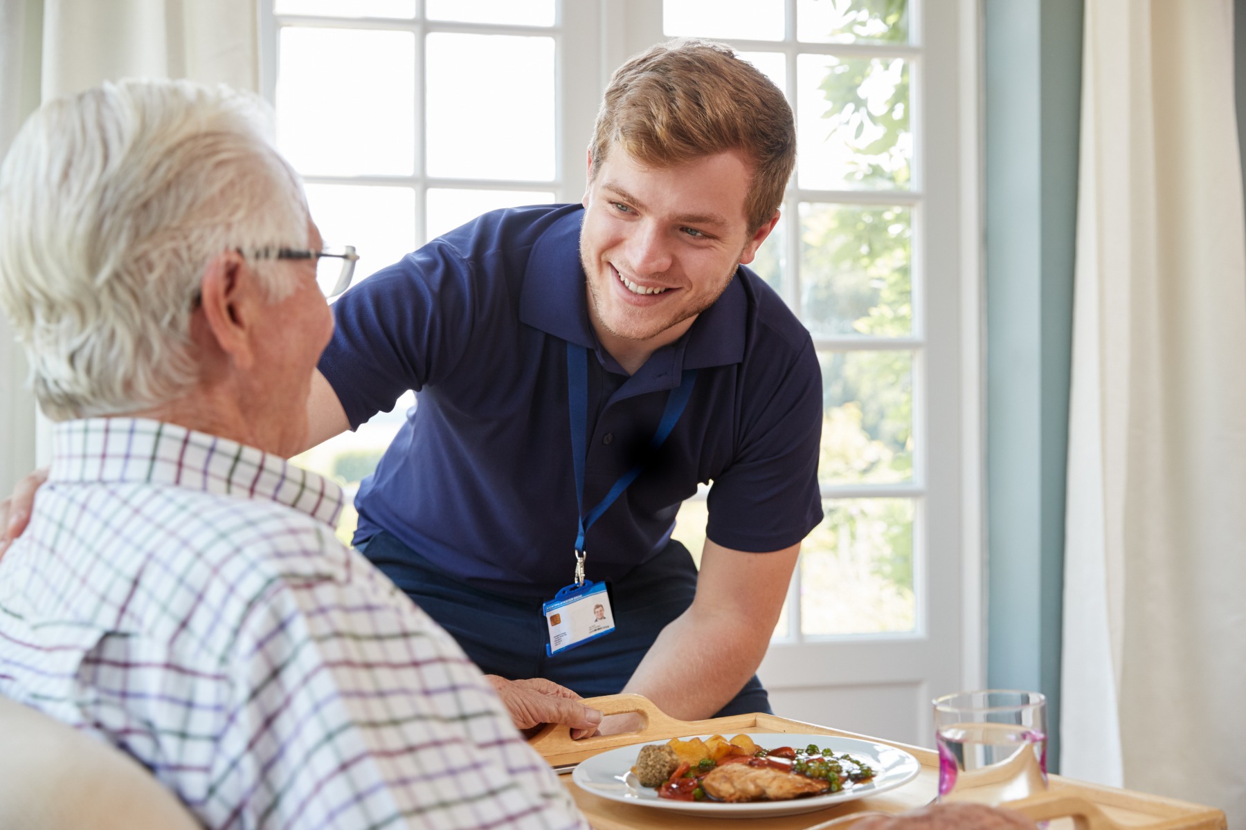 carer giving elderly man food